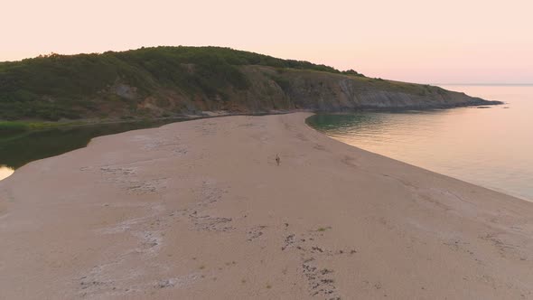 Couple Walking on Narrow Strip of Sand Between River and Sea at Sunset at Sinemorets, Bulgaria alt