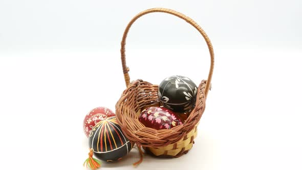 Decorative Basket with Painted Easter Eggs on White Background