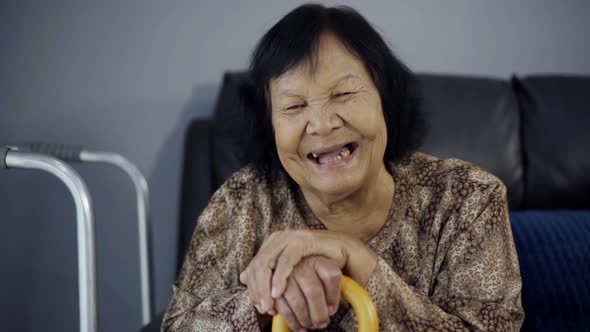 slow-motion of senior woman laughing and holding wooden cane in living room