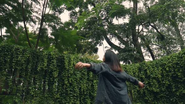 Young Asian woman deeply in a forest to enjoy and listen to music on smartphone.