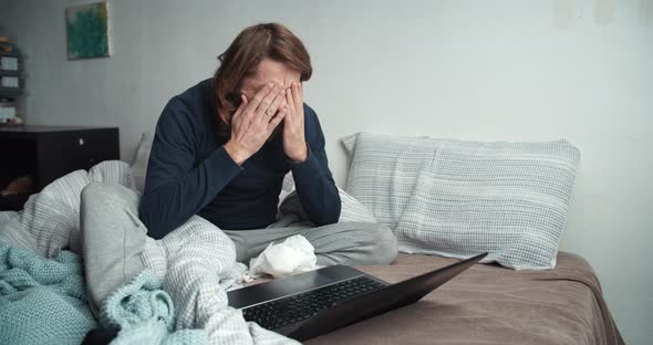 Freelance Man Working at Home Having Illness Cold and Flu Sitting on Bed