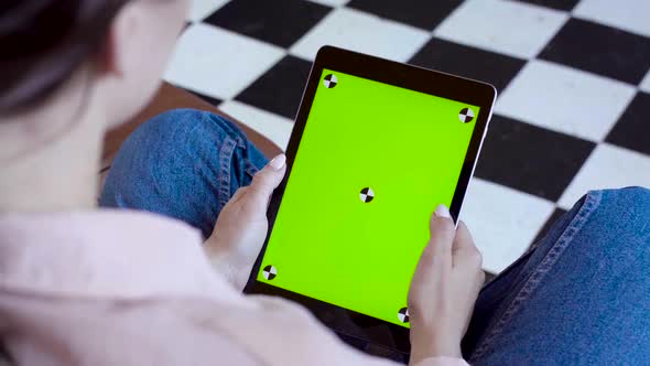 Close-up of woman holding tablet and touching green screen alt