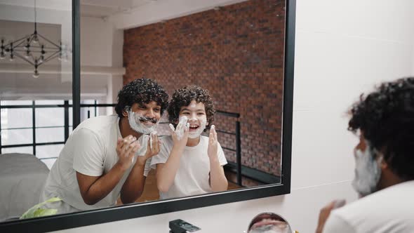 Elder and Younger Brothers Put Foam for Shaving on Face alt