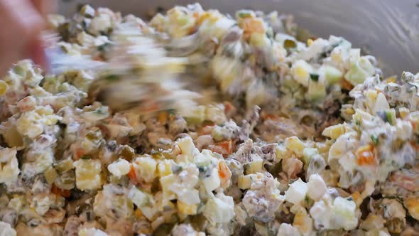 the Hands of the Cook Holding a Large Spoon Stir a Lot of Olivier Salad in a Large Culinary Bowl