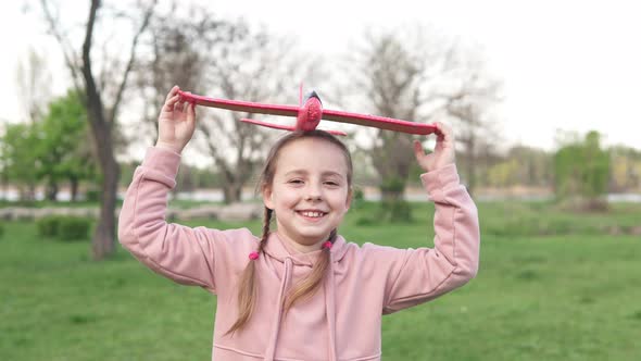 A girl in the park plays with a toy plane, she wants to become an astronaut. Dreamer pilot. alt
