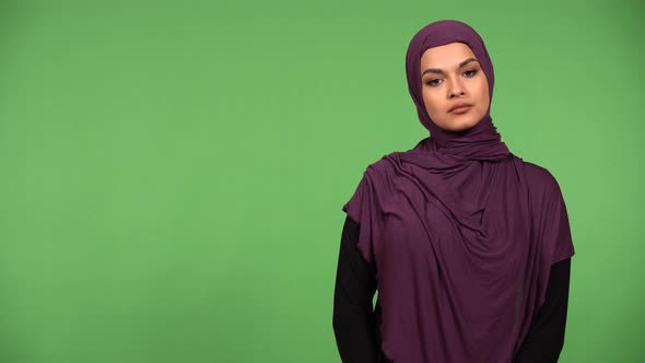 A Young Beautiful Muslim Woman Looks Seriously at the Camera  Green Screen Background