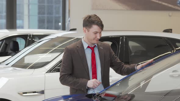 Mature Male Customer Examining Modern Automobile for Sale at the Dealership alt