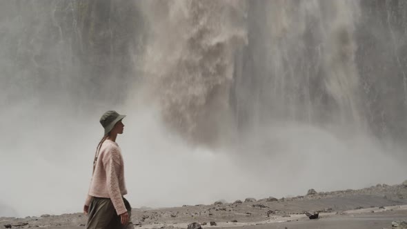Young woman traveler in hat going near Karakaya-Su waterfall, Dzhily-Su, North Caucasus, travelling