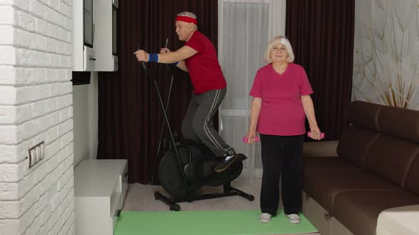 Senior Man Woman Doing Vitality Weight Lifting Sport Dumbbells Exercises and Using Orbitrek at Home alt