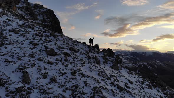 Aerial View Silhouettes of Two Tourists Man and Woman Stand High in the Mountains Against the alt