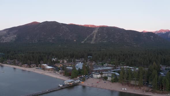 Reverse pullback and panning aerial shot of South Lake Tahoe at low light in the summer. 4K alt