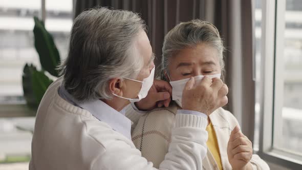 Two elderly Asian couples wearing masks hug and encourage each other. alt