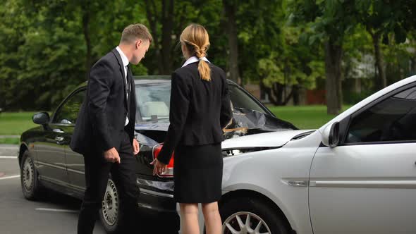 Drivers Observing Car Damage and Arguing After Road Collision on Parking Lot alt