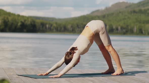 Sportive Woman Having Yoga Practice Outdoors on Lake Pier alt
