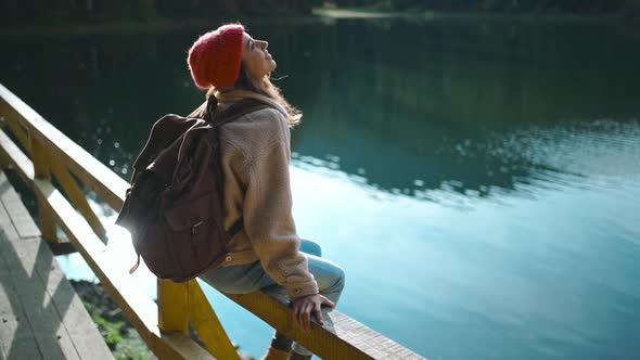 Slow Motion Inspired Joyful Woman Hiker Sits on Wooden Pier at Beautiful Mountain Lake with alt