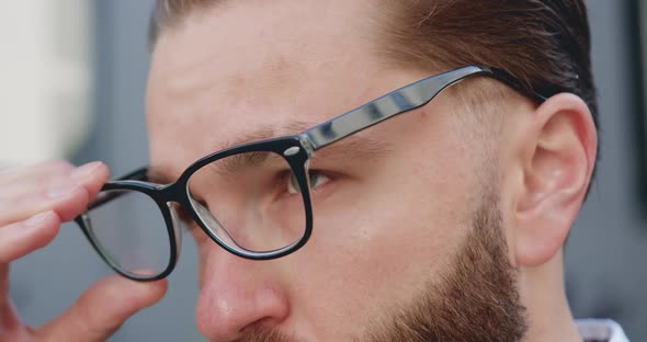 Man with Green Eyes Which Putting on His Glasses and Looking Into the Distance alt