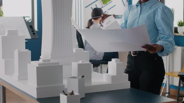 Close Up of Woman Engineer Analyzing Blueprints Plan and Building Model for Development alt