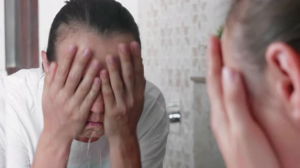 Young Woman is Washing Her Face in Front of the Mirror in Bathroom