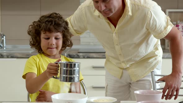 Father and Son Cooking in Kitchen at Home, Sifting Flour