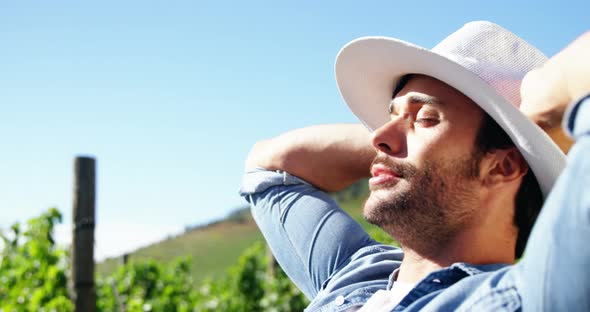Male farmer relaxing with hands behind back at a vineyard alt
