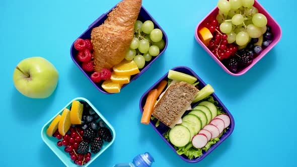 Shot of School Lunchboxes with Various Healthy Nutritious Meals on Blue Background