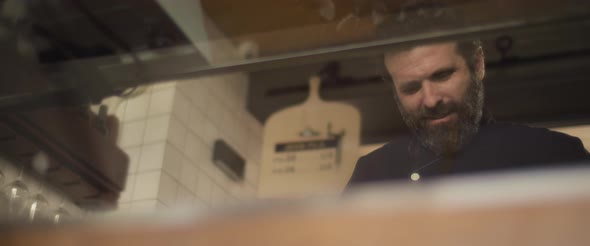 A bearded hispanic chef working in the restaurant kitchen. Slow motion, medium shot. alt
