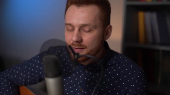 Closeup Face of Handsome Guitarist Singer Man Playing Guitar and Singing Into Microphone While alt