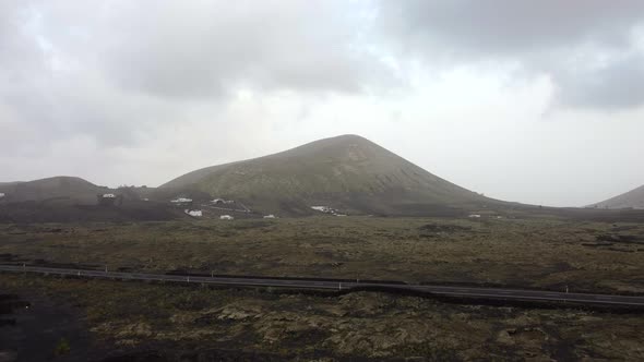 Cars driving in Lanzarote with volcano in background. Extreme travel and adventure footage alt