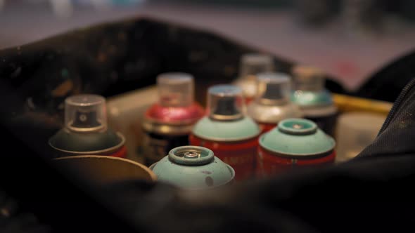 Isolated colorful spray paints ready for street art, with blurry people on the background. Graffiti alt
