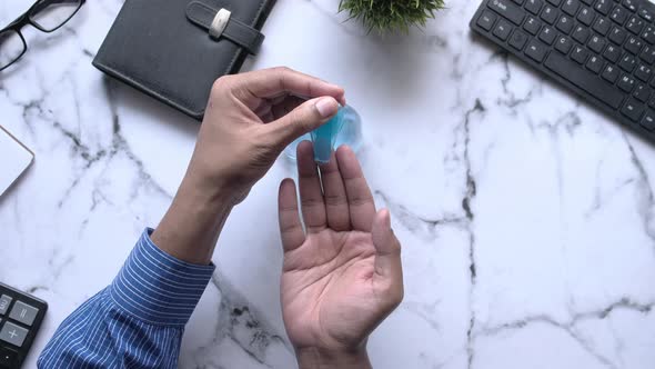 Businessman Using Sanitizer Gel on Office Desk Top Down  alt