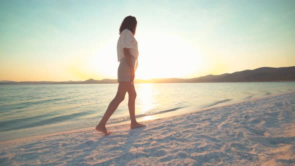 Female Model Walking on the White Sandy Beach of the Clear Tropical Turquoise Sea at Sunset alt