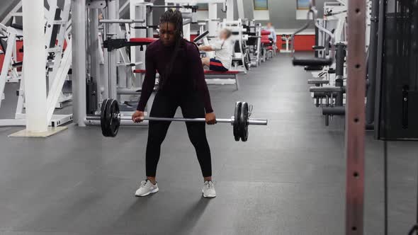 Sports in the Gym  Strong Black Woman Pulling Up a Dumbbell in a Gym alt