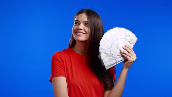 Smiling Happy Woman with Cash Money  USD Currency Dollars Banknotes on Blue Wall alt
