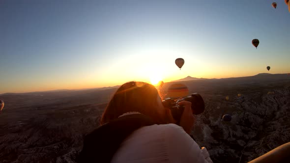 Girl taking pictures in hot air balloon at sunrise, Cappadocia, Turkey alt