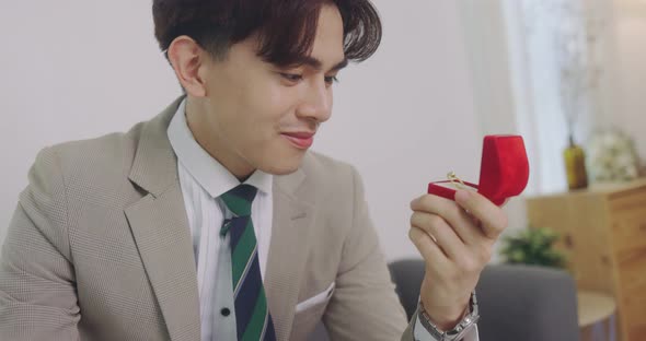 Slow Motion Handsome Asian Groom Opening A Red Ring Box And Looking Wedding Ring The Box. alt
