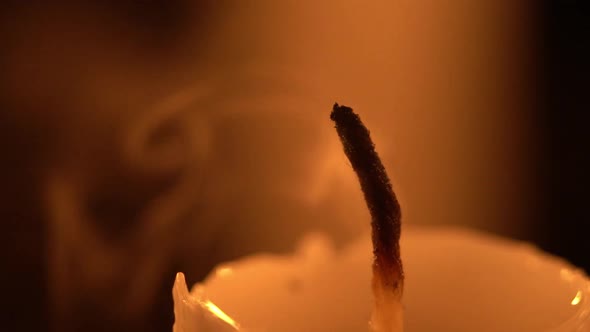 Macro view of extinguishing a candlelight by blowing it out in slow motion