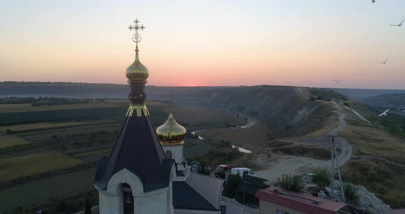 pigeons flying around a golden dome of church in orheiul vechi, moldova alt