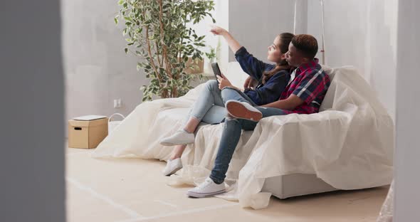 Couples of Different Nationalities are Sitting on Couch in Living Room in Newly Purchased Apartment alt