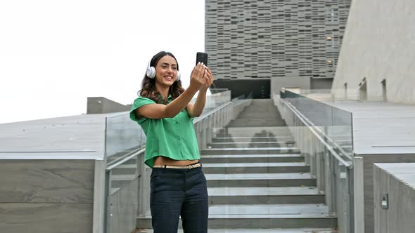 Smiling woman taking smartphone selfie dancing with headphones