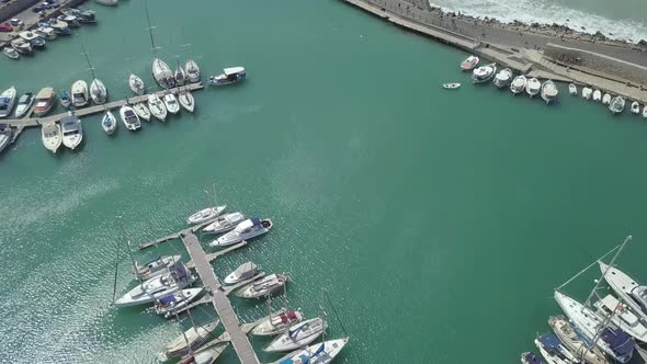 Aerial view of old port with sail boats near fortress, waves breaking against wall, Heraklion, Crete