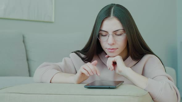 Woman using tablet. Young caucasian millennial with glasses tapping tablet.