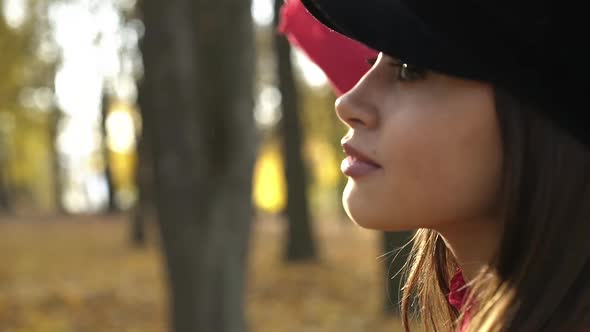 Young Girl Stretching Hand to the Sun and Posing at Camera in Autumn Park alt