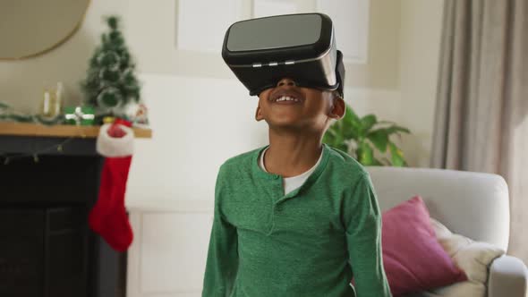Animation of happy african american boy wearing vr headset and having fun at christmas time alt