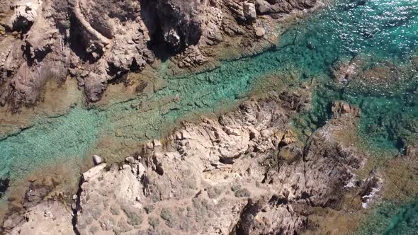 Drone soars over a rock in the middle of the sandy beach of Chia in Sardinia's south, stunning weath alt