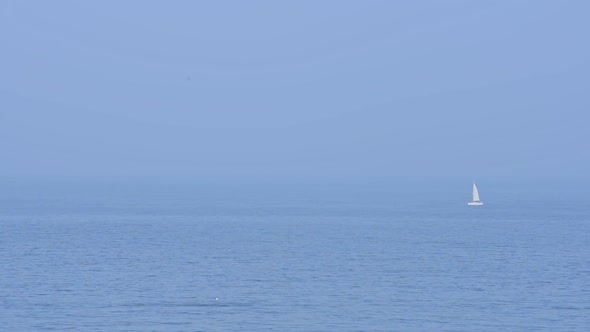 A white sailboat sailing on the blue waves of England - wide shot alt