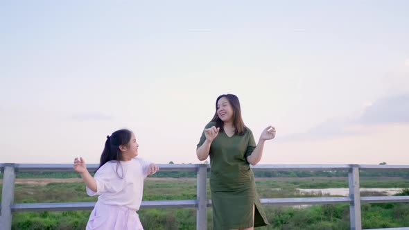 Asian mom and kid are on vacation. Spending time outdoor and dancing together