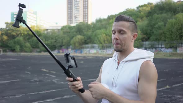 Handsome Man Preparing an Action Camera for Shooting in the Stadium alt