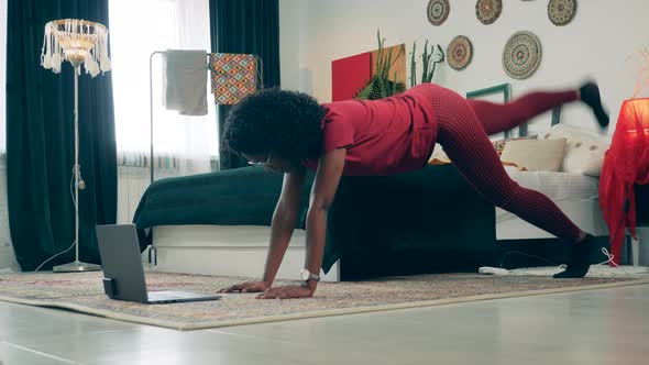 African Woman Is Exercising at Home with a Video Tutorial alt