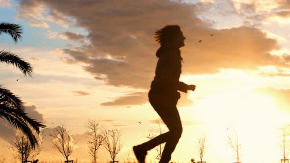 Slow motion of a thin woman silhouette running at sunset in a park in Istanbul.