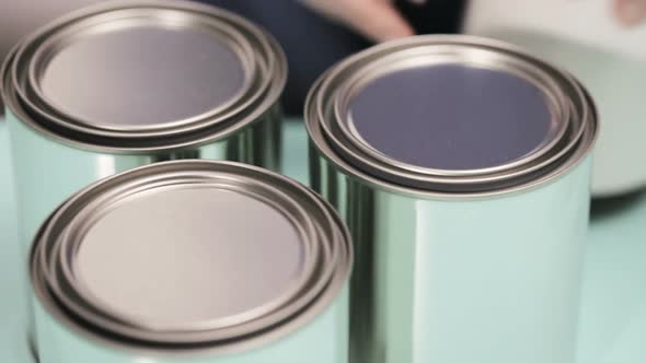 Supplies to start house painting project. Metal paint cans, paint brushes, and paint swatches. alt